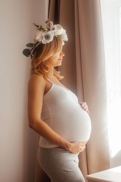 Foto la donna incinta resta nella stanza e guarda la finestra concetto di gravidanza di bellezza