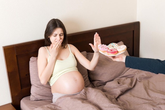 Foto la donna incinta che rimane a letto rifiuta di mangiare cibo spazzatura come le ciambelle e non fa alcun gesto