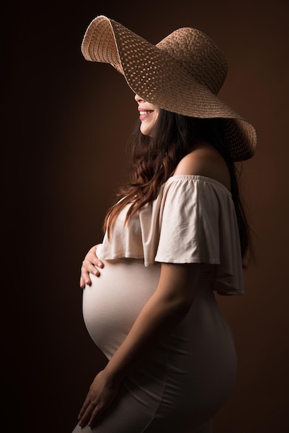 Photo a pregnant woman in a straw hat and a straw hat