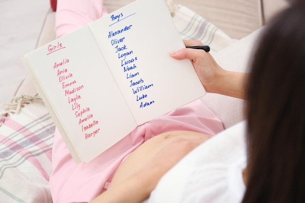 Foto donna incinta che studia l'elenco dei nomi a casa concetto di scelta del nome del bambino