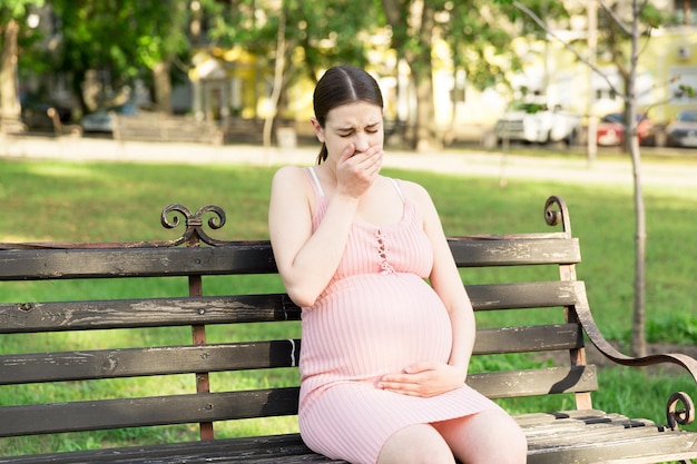 pregnant woman suffering from toxicosis in the park