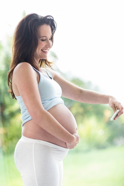 Pregnant woman taking a picture of her belly in front of a window