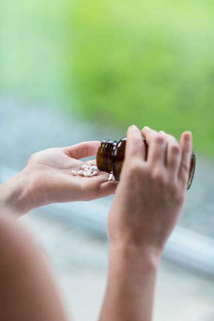 Pregnant woman taking a pill in her bedroom