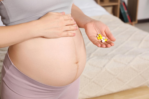 Pregnant woman taking pills at home closeup Space for text