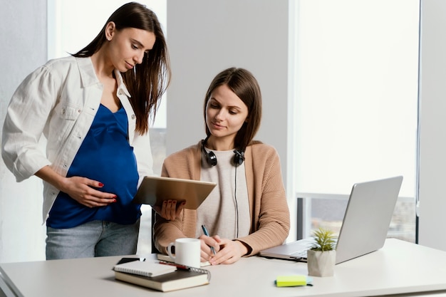 Photo pregnant woman talking to her coworker