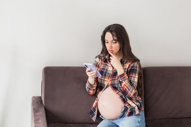 写真 電話で話している妊婦ソファに座っている若い妊婦