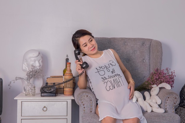 Photo pregnant woman talking on rotary phone while sitting at home