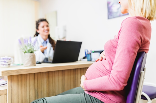 Pregnant woman talking with her doctor at clinic.