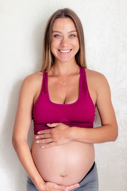 Pregnant woman touching belly while smiling