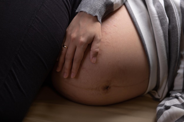 Foto donna incinta che tocca la sua pancia nel letto maternità e aspettativa di gravidanza