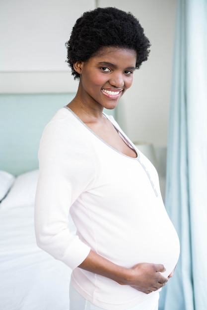 Pregnant woman touching her belly in bedroom