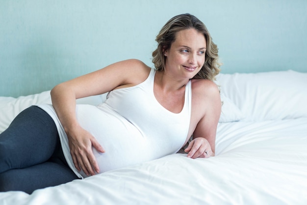 Pregnant woman touching her belly in her bedroom