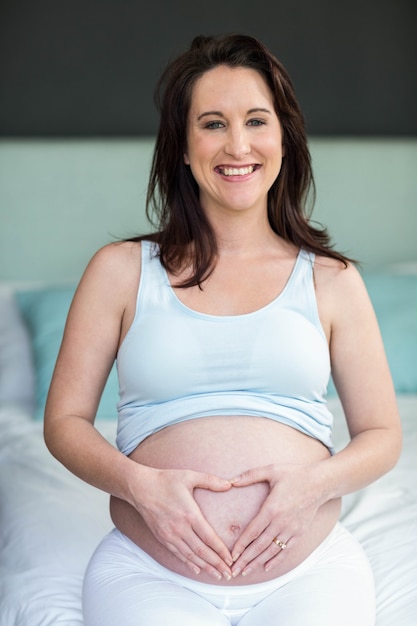 Pregnant woman touching her belly in her bedroom