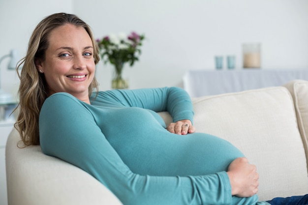 Pregnant woman touching her belly lying on the couch