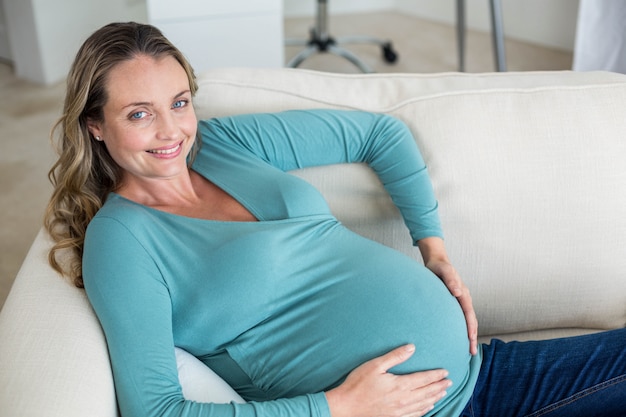 Pregnant woman touching her belly lying on the couch