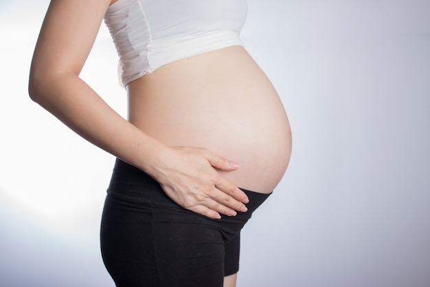 Pregnant woman touching her belly with hands 