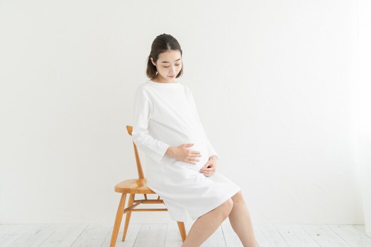 Photo 妊娠中の女性がおなかに触れて