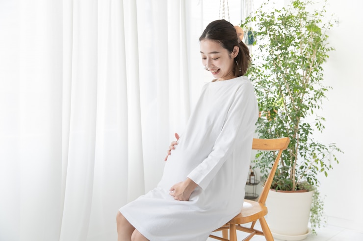 Photo 妊娠中の女性がおなかに触れて