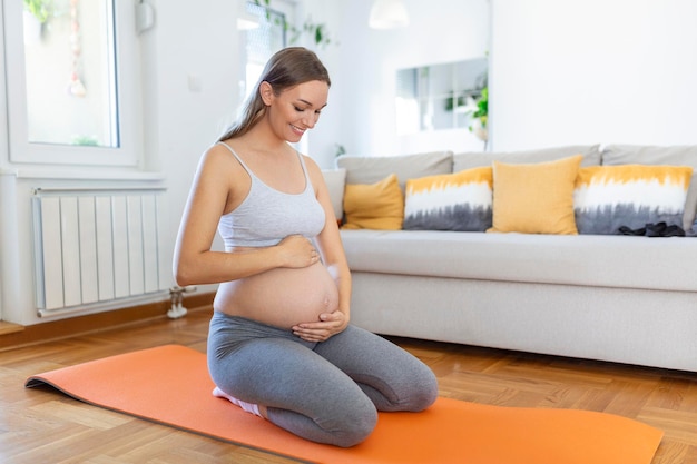 Pregnant woman training yoga caressing her belly young happy\
expectant relaxing thinking about her baby and enjoying her future\
life motherhood pregnancy yoga concept