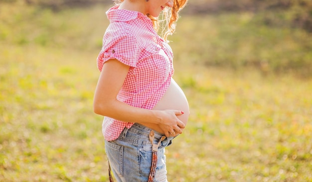 A pregnant woman trains yoga in a hero\'s pose caresses her\
belly young happy future is resting thinking about her child and\
enjoying her future life motherhood pregnancy