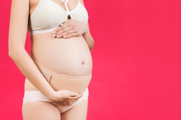 pregnant woman in underwear wearing elastic pregnancy bandage