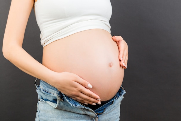 Donna incinta in jeans decompressi che mostra il suo pancione