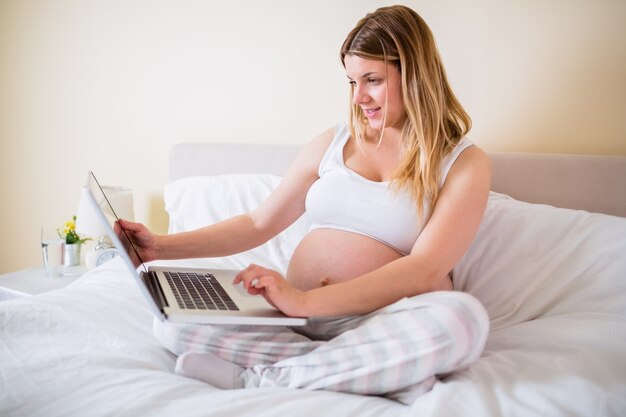 Donna incinta che per mezzo del computer portatile