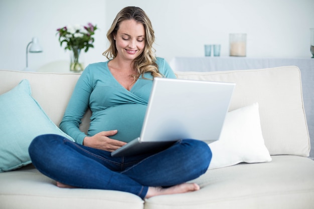 Pregnant woman using a laptop on the couch