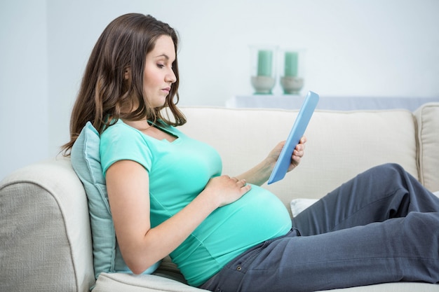 Pregnant woman using tablet on couch