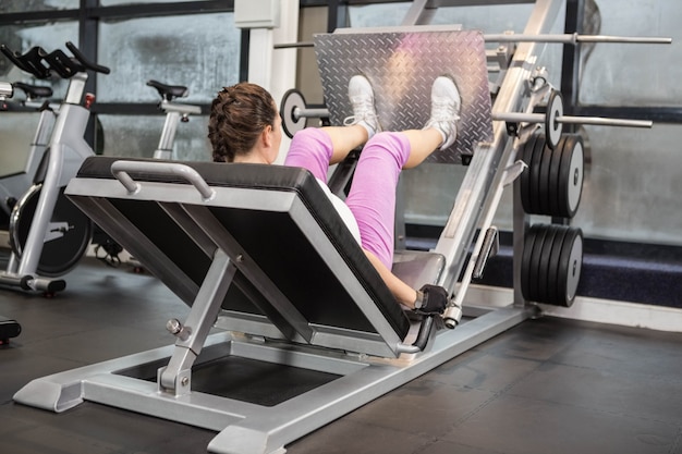 Pregnant woman using weight machine at the gym