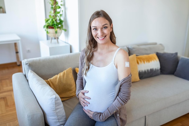 Pregnant Woman Vaccinated Against Covid-19 Showing Arm With Plaster Bandage After Coronavirus Vaccine Injection Sitting . Smiling To Camera.