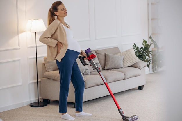 Pregnant woman vacuuming home with rechargeable vacuum cleaner