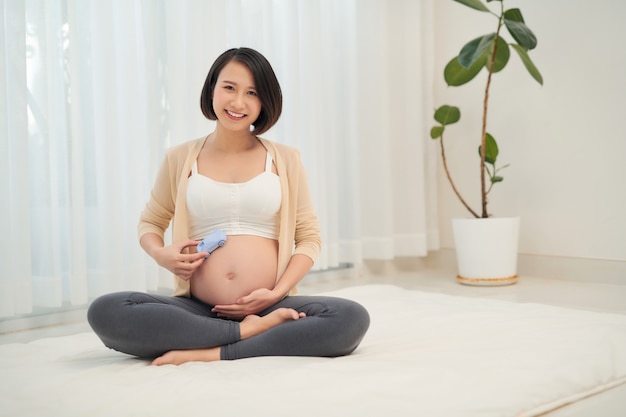 Pregnant woman waiting a baby boy with car toy in arms