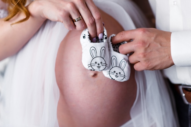 Pregnant woman waiting for a desired baby. Baby socks on belly of pregnant woman