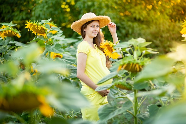 Una donna incinta cammina in un campo di girasoli