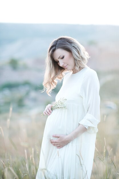 Pregnant woman wearing dress posing outdoors over nature