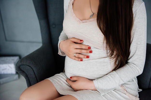 Pregnant woman in white dress holding her belly