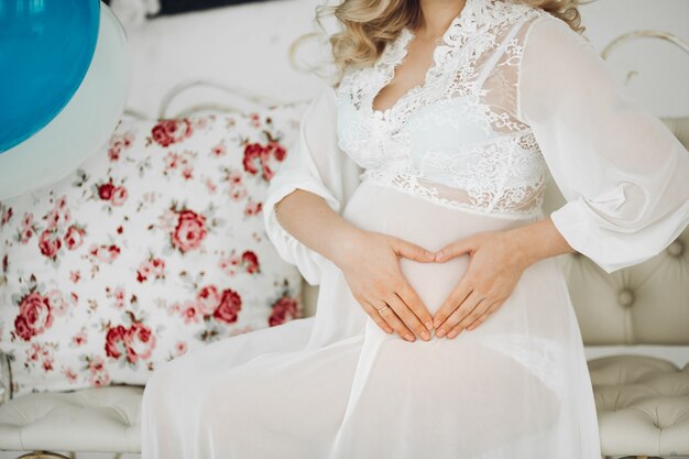 Pregnant woman in white holding hands