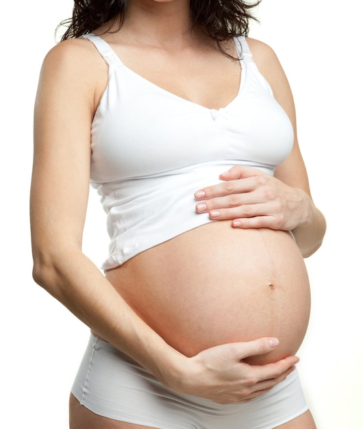 Pregnant woman in a white suit touching her belly