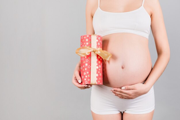 pregnant woman in white underwear holding a gift box