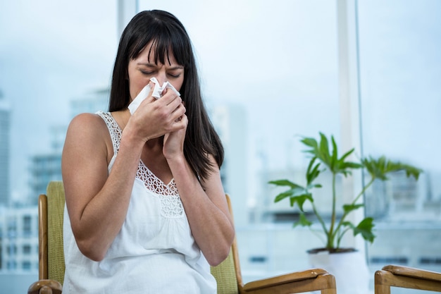 Pregnant woman wiping nose  at home