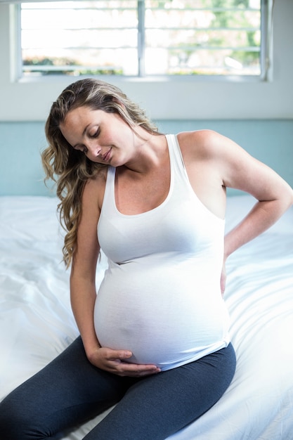 Photo pregnant woman with back pain sitting on her bed