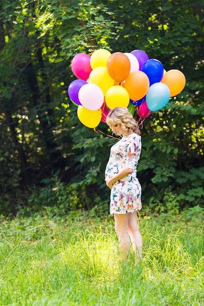 Pregnant woman with balloons outdoors