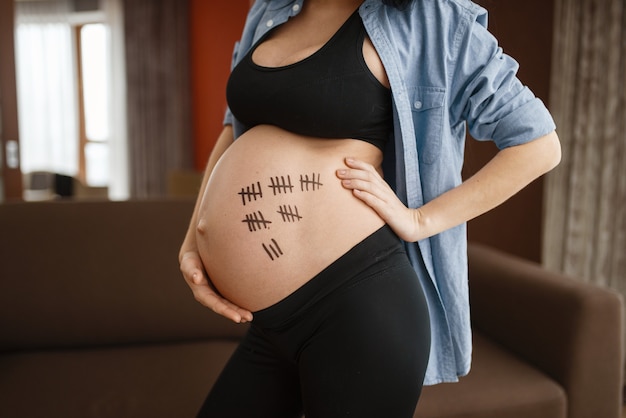 自宅で腹のポーズを持つ妊娠中の女性、側面図。妊娠中、出生前は落ち着いている。妊娠中の母親が寝室で休んでいる、健康的なライフスタイル