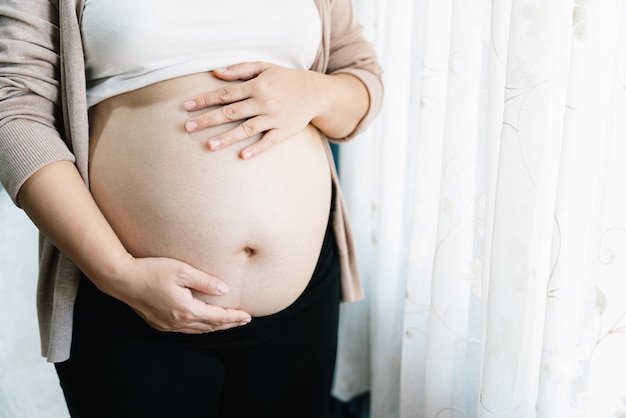 Pregnant woman with big belly at window pregnancy motherhood people and expectation concept mother