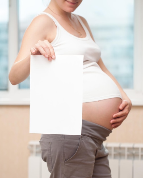 Photo the pregnant woman with a clean sheet of paper for text