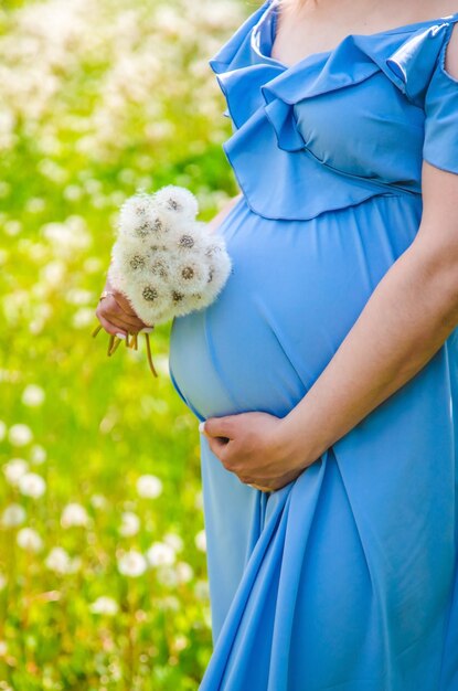 Pregnant woman with dandelions in the garden selective focus