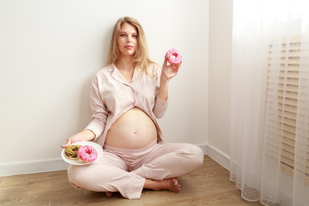 Pregnant woman with donuts on the floor at home