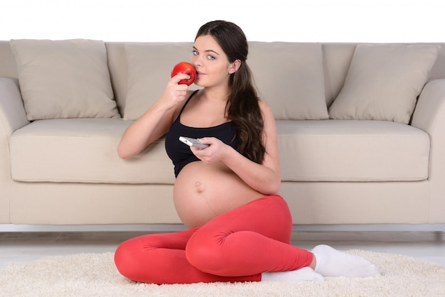 Pregnant woman with fruits sitting on the floor.