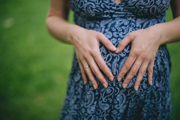 腹の上に手を持つ妊娠中の女性